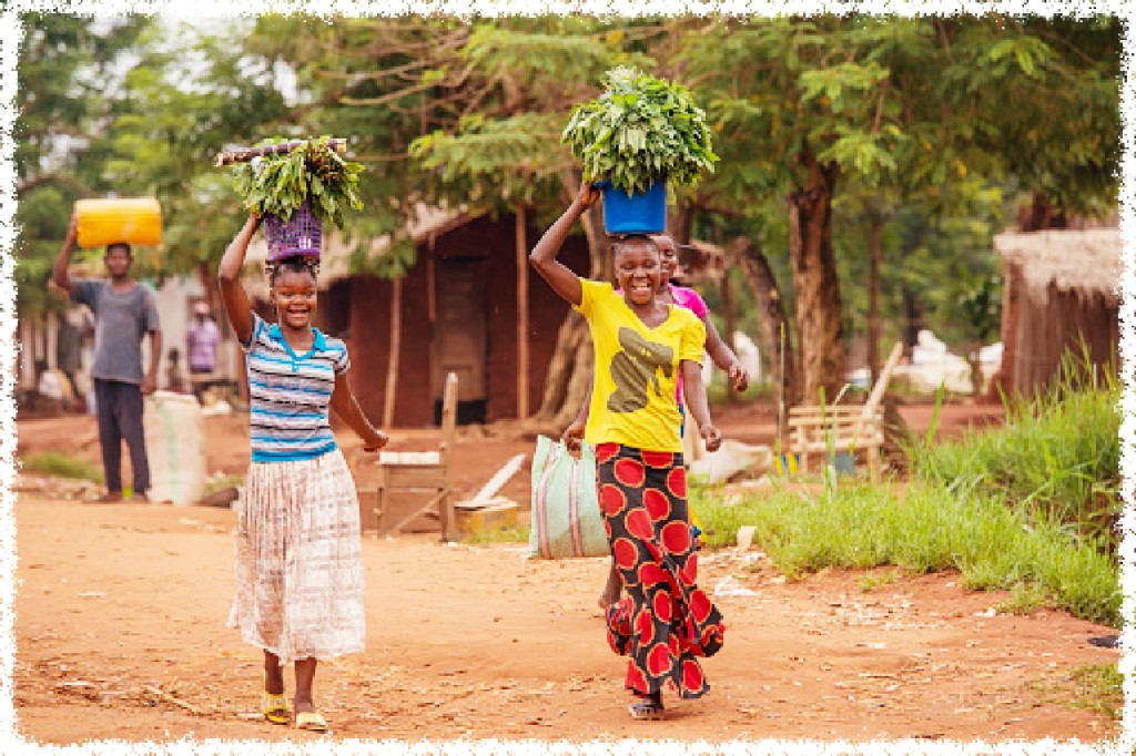 Karawa, Democratic Republic of Congo - August 24, 2013: Two Women carrying food (vegetables) on their heads on an unpaved road in rural Congo, province of Equateur. Walking and bicycling is nearly the only way of transportation in the poor regions of Congo.